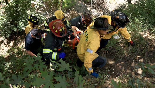 Santa Rosa and So<em></em>noma County Fire District firefighters use teamwork to bring an injured woman out of Mark West Creek, Thursday, June 28, 2023 after the car she was a passenger in rolled down from Mark West Springs Road and landed upside down.  The woman was airlifted to a local hospital by CHP. (Kent Porter / The Press Democrat) 2023