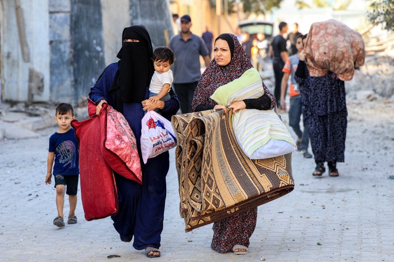 Palestinian women walk with children and belo<em></em>ngings as they flee an area in the aftermath of an Israeli air strike in Rafah in the southern Gaza Strip