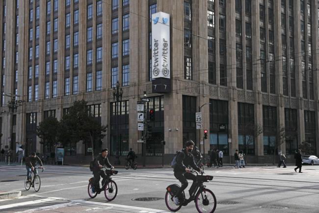 People cycle on Market Street past Twitter headquarters Friday, Nov. 4, 2022, in San Francisco. (Lea Suzuki/San Francisco Chro<em></em>nicle via AP)