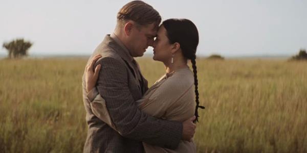 Leo<em></em>nardo DiCaprio as Ernest Burkhart and Lily Gladstone as Mollie Burkhart in a field in Killers of the Flower Moon