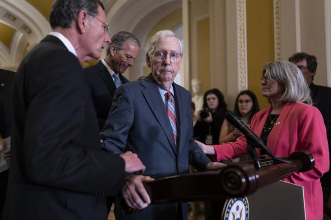 Senate Minority Leader Mitch McConnell, R-Ky., center, is helped by, from left, Sen. John Barrasso, R-Wyo., Sen. John Thune, R-S.D., and Sen. Joni Ernst, R-Iowa, after the 81-year-old GOP leader froze at the micropho<em></em>nes as he arrived for a news conference, at the Capitol in Washington, Wednesday, July 26, 2023. McCo<em></em>nnell went to his office for a few minutes and returned to speak with reporters. (AP Photo/J. Scott Applewhite)