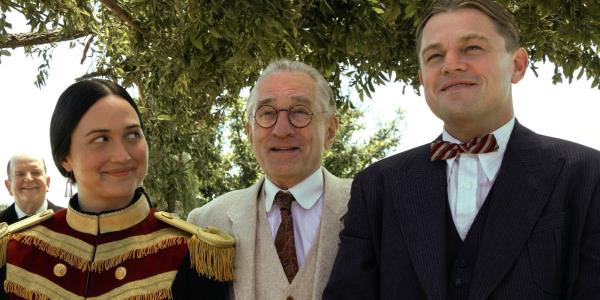 Lily Gladstone, Robert De Niro, and Leo<em></em>nardo DiCaprio smiling together in Killers of the Flower Moon