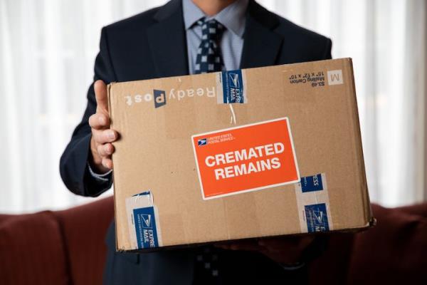 Funeral director Archer Harmon poses for a portrait with a box of cremated human remains at Fairfax Memorial Funeral Home in Fairfax, Virginia, on March 1, 2021. The remains were those of a veteran and were to be sent to Arlington Natio<em></em>nal Cemetery.