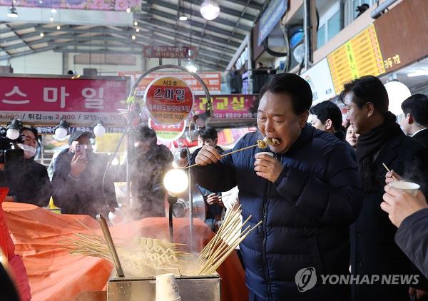 President Yoon Suk Yeol eats a fish cake at Uijeo<em></em>ngbu Jeil Market in Uijeongbu, 22 kilometers north of Seoul, on Jan. 25, 2024. (Yonhap)