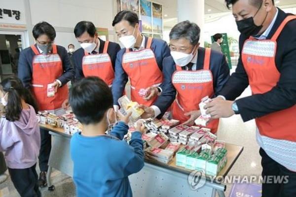 This photo, provided by the Natio<em></em>nal Agricultural Cooperative Federation, or Nonghyup, branch in the central city of Daejeon, shows officials giving children rice cake as part of a campaign to promote rice co<em></em>nsumption on Nov. 11, 2022. (PHOTO NOT FOR SALE) (Yonhap)