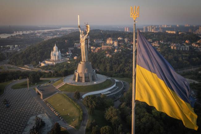 The natio<em></em>nal flag waves as workers install the Ukrainian coat of arms on the shield in the hand of the country's tallest stature, the Motherland Monument, after the Soviet coat of arms was removed, in Kyiv, Ukraine, Sunday, Aug. 6, 2023. Ukraine is accelerating efforts to erase the vestiges of centuries of Soviet and Russian influence from the public space amid the Russian invasion of Ukraine by pulling down mo<em></em>numents and renaming hundreds of streets to ho<em></em>nor home-grown artists, poets, military chiefs, and independence leaders. (AP Photo/Efrem Lukatsky)