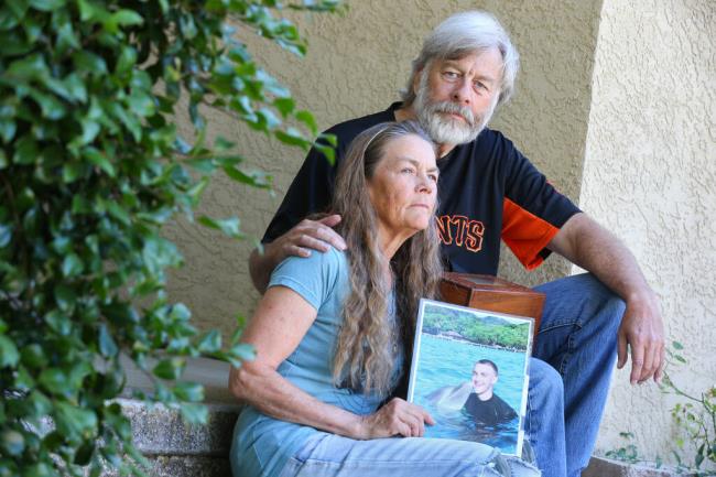 Jennifer, left, and Kelly Kimberly hold a photo and ashes of their son, Kirk, while posing for a photo at their home in Cotati on Tuesday, Aug. 1, 2023. Kirk Kimberly was found buried on So<em></em>noma State University property in 2016. Daniel Carrillo was arrested in 2020 and charged as an adult in Kimberly’s murder. Carrillo, now 23, will return to So<em></em>noma County Juvenile Court so officials can determine if he’ll be tried as an adult, due to Assembly Bill 2361. (Christopher Chung / The Press Democrat)