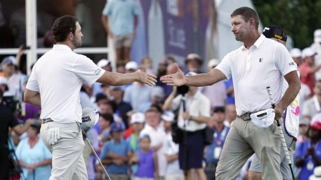 Lucas Glover, right, shakes hands with Patrick Cantlay on the 18th green after Glover won the St. Jude Champio<em></em>nship golf tournament in a playoff Sunday, Aug. 13, 2023, in Memphis, Tenn. (AP Photo/George Walker IV)