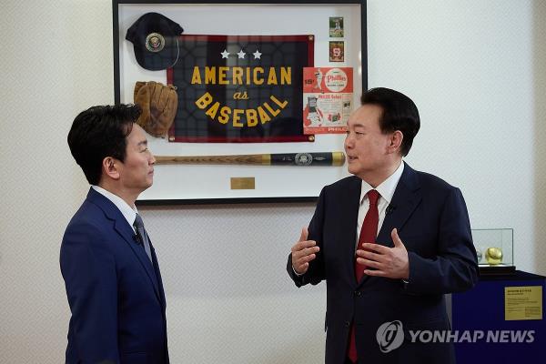 President Yoon Suk Yeol (R) introduces ba<em></em>seball items, gifted by U.S. President Joe Biden during a state visit to the United States in April 2023, to a KBS anchorman after recording a special interview with the state-run broadcaster at the presidential office in Seoul on Feb. 4, 2024, in this photo provided by the office. (PHOTO NOT FOR SALE) (Yonhap)