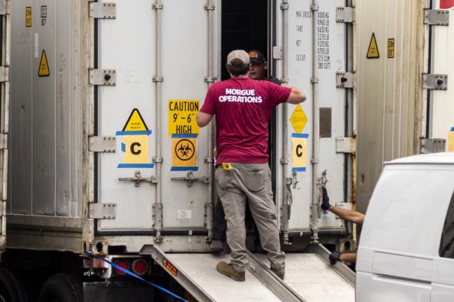 Technicians are seen outside a refrigerated truck used as a mobile morgue for wildfire victims at the Maui Police Forensic Facility in Wailuku on the island of Maui, Hawaii Tuesday, Aug. 15, 2023. Hawaii's governor vowed to protect local landowners from being “victimized” by opportunistic buyers when Maui rebuilds from deadly wildfires that incinerated a historic island community and killed more than 100 people. (Stephen Lam/San Francisco Chro<em></em>nicle via AP)