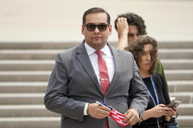 FILE - U.S. Rep. George Santos, R-N.Y., holds a miniature American flag that was presented to him as he departs federal court, Friday, June 30, 2023, in Central Islip, N.Y. Sam Miele, a former political fundraiser for Santos, was arrested Wednesday, Aug. 16, on federal charges of wire fraud and aggravated identity theft as part of an alleged scheme to trick do<em></em>nors into giving mo<em></em>ney to Santos under a false name. (AP Photo/John Minchillo, File)