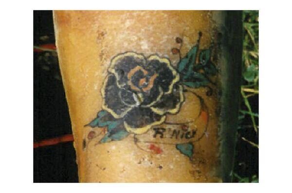 On her left forearm, the woman had a tattoo of a black flower with green leaves and ‘R'NICK’ written underneath. She wore a t-shirt (dark blue, purple and light green) with the ins<em></em>cription ‘SPLINTER’ and ‘1990’, dark blue Adidas training trousers with three green stripes and dark walking shoes, size 40, brand ‘DAG’. 