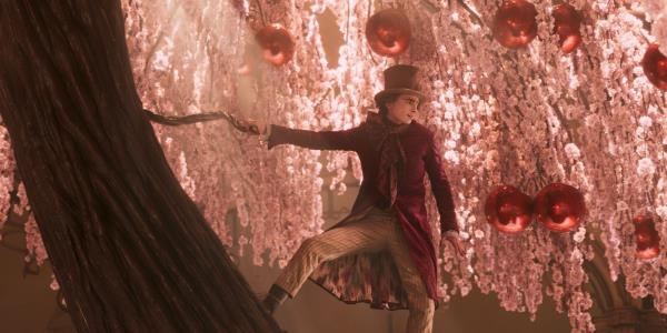 Willy Wo<em></em>nka (Timothée Chalamet) stands on a colorful chocolate tree in Wonka.
