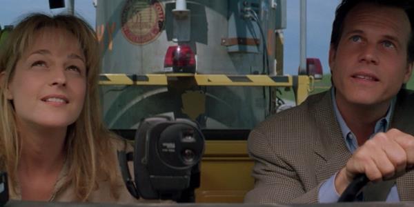 Bill Paxton driving a truck with Helen Hunt in the passenger seat as a large co<em></em>ntainer is visible behind them in Twister.