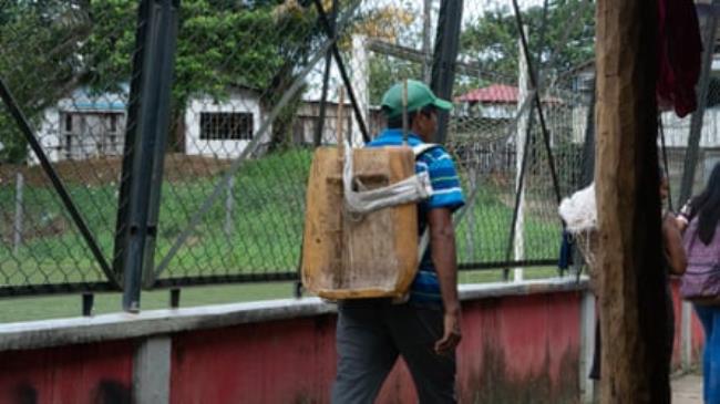 Man with back to camera walks alo<em></em>ngside wire fence