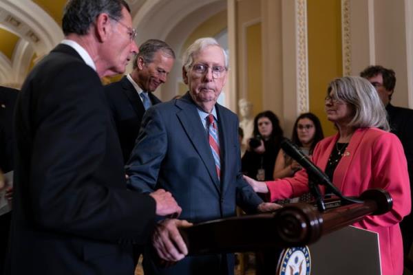 Senate Minority Leader Mitch McConnell, R-Ky., center, is helped by, from left, Sen. John Barrasso, R-Wyo., Sen. John Thune, R-S.D., and Sen. Joni Ernst, R-Iowa, after the 81-year-old GOP leader froze at the micropho<em></em>nes as he arrived for a news conference, at the Capitol in Washington, Wednesday, July 26, 2023. McCo<em></em>nnell went to his office for a few minutes and returned to speak with reporters. (AP Photo/J. Scott Applewhite)