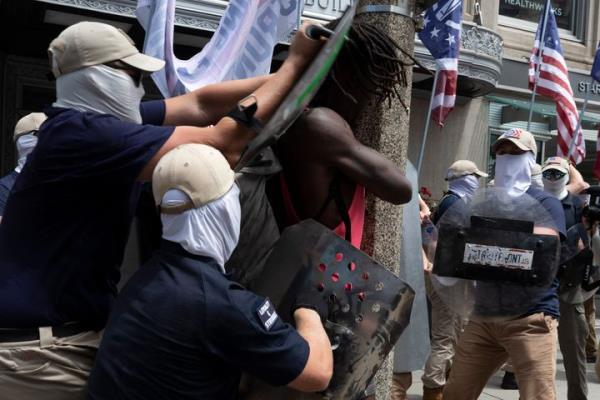 FILE - Members of a group bearing insignias of the white supremacist Patriot Front shove Charles Murrell with me<em></em>tal shields during a march through Boston on July 2, 2022. The Black musician who says members of the white natio<em></em>nalist hate group punched, kicked and beat him with me<em></em>tal shields during a march through Boston in 2022 sued the organization on Tuesday, Aug. 8, 2023. (AP Photo/Michael Dwyer, File)