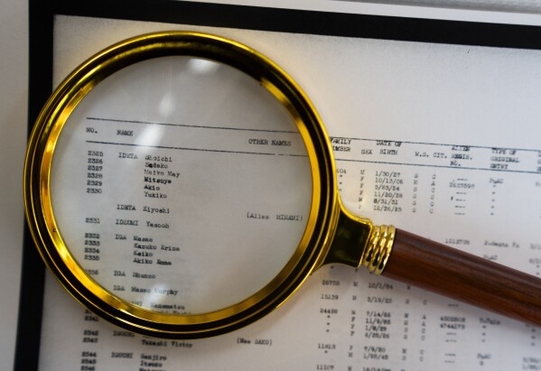 A magnifying glass sits over a page of camp records for Associated Press Photographer Lindsey Wasson's maternal grandfather Akio Ideta and family, in the visitor center at Minidoka Natio<em></em>nal Historic Site, Sunday, July 9, 2023, in Jerome, Idaho. (AP Photo/Lindsey Wasson)