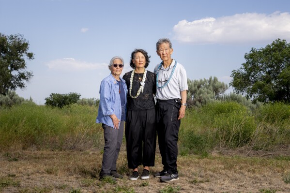 Minidoka Pilgrimage co-chair Erin Shigaki, center, poses with parents Polly Shigaki, left, and John Shigaki, right, at Minidoka Natio<em></em>nal Historic Site, Saturday, July 9, 2023, in Jerome, Idaho. John was born at Minidoka, delivered by a horse veterinarian, while Polly, whose parents were matched and married there, was born in Cleveland after they left camp. "I think the pilgrimage is just so im<em></em>portant for people to be able to to grapple with the questions that they have...And for it to be a safe place to ask and wo<em></em>nder and have these emotions and and therefore heal," Erin Shigaki said. (AP Photo/Lindsey Wasson)