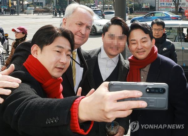 Ex-football star Lee Chun-soo (L) and former Land Minister Won Hee-ryong (R) of the ruling People Power Party take photos with citizens as part of the election campaign for Won at his co<em></em>nstituency in Incheon, just west of Seoul, on Feb. 26, 2024, in this file photo. (Yonhap)