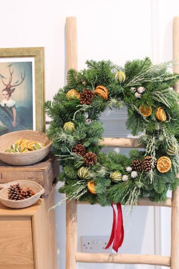  Paper Daisy's Christmas wreaths are made from foraged foliage, decorated with pine co<em></em>nes and orange slices.