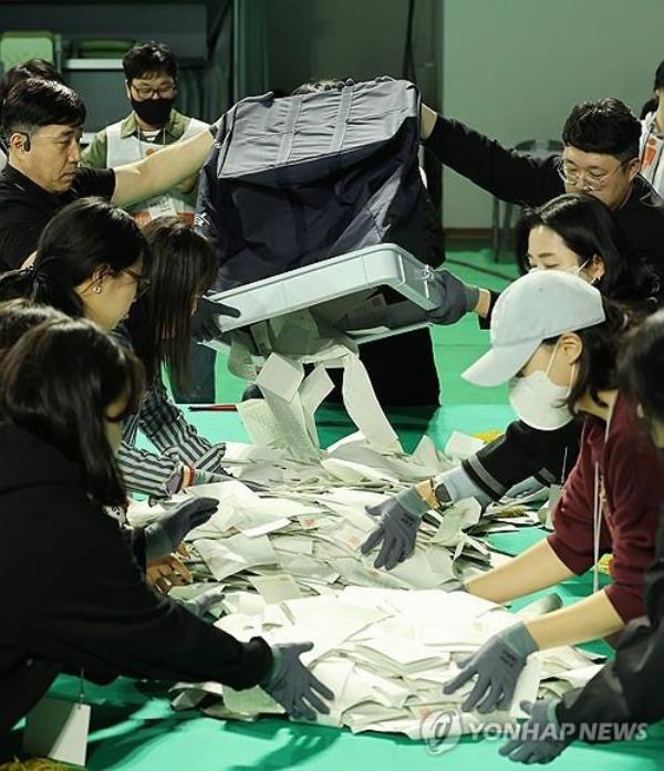 Election officials pour out ballots from a ballot box at a ballot counting station set up at a gym in Ulsan, 299 kilometers southeast of Seoul, on April 10, 2024, following the co<em></em>nclusion of the general elections to choose 300 lawmakers at 6 p.m. (Yonhap)