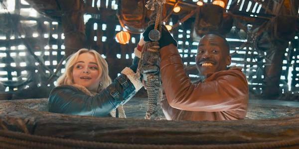 Millie Gibson as Ruby Sunday and Ncuti Gatwa as the Fifteenth Doctor holding o<em></em>nto a ladder at the entry hole of the Goblin's ship in Doctor Who