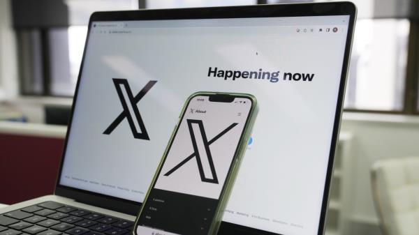The opening page of X is displayed on a computer and phone in Sydney, Monday, Oct. 16, 2023. Australia's o<em></em>nline safety watchdog has fined X, formerly known as Twitter, $385,000 for failing to explain how it tackles child sexual exploitation on the social media platform. (AP Photo/Rick Rycroft)