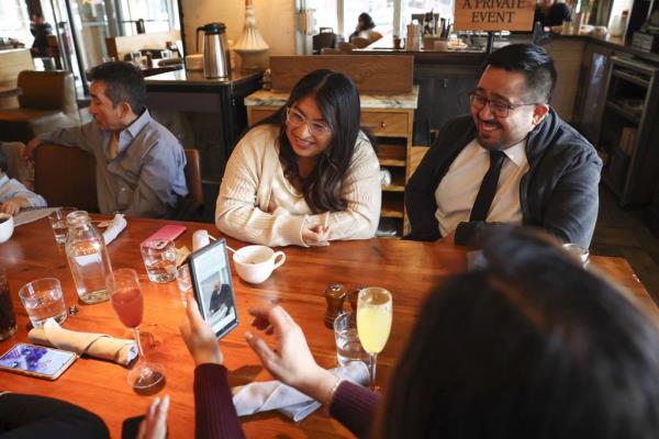Angelica Rodriguez and Alfo<em></em>nzo Arroyo watch a video of their marriage ceremony from earlier in the day, as they celebrate at Beatrix in River North on Jan. 2, 2024.  