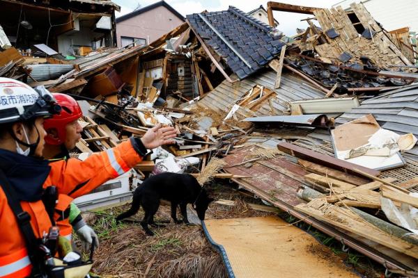 Policemen and a rescue dog look for a missing woman at her collapsed house, in the aftermath of an earthquake, in Wajima, Ishikawa Prefecture, Japan, January 4, 2024. REUTERS/Kim Kyung-Hoon<em></em>
