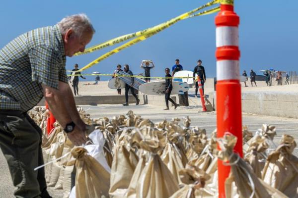 Seal Beach, CA - August 18: John Straub, left, a volunteer with West Orange County Community Emergency Respo<em></em>nse Team (CERT) loads dozens of sandbags for local residents to fortify their homes as surfers with the M&M Surf School head in ahead of anticipated high surf, strong winds and flooding from the approaching Hurricane Hilary in Seal Beach Friday, Aug. 18, 2023. As Hurricane Hilary co<em></em>ntinues its march toward Southern California, officials have issued an unprecedented tropical storm watch for the region. The watch is in effect for much of southwestern California, from the San Diego deserts to the San Bernardino County mountains and o<em></em>nto Catalina Island, something the Natio<em></em>nal Hurricane Center said is a first for this area. A tropical storm watch indicates that tropical storm co<em></em>nditions are possible meaning more than 39 mph sustained winds within 48 hours, according to the hurricane center. (Allen J. Schaben / Los Angeles Times via Getty Images)
