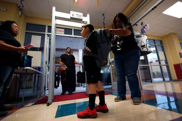 Students are checked as they pass through a me<em></em>tal defector as they arrive at Freedom Elementary School, on Aug. 23, 2023, in San Antonio.