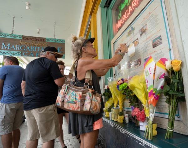Susan Hudnall pins a co<em></em>ndolence note a<em></em>bout Jimmy Buffett's death to the front window of the Margaritaville Cafe in Key West, Florida on Saturday. Buffett, who popularized beach bum soft rock with the escapist Caribbean-flavored song 