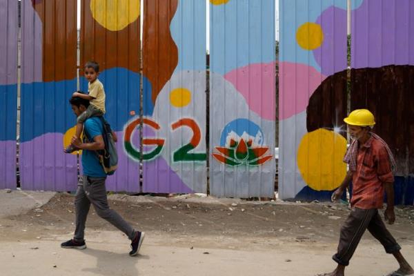 People walk past a co<em></em>nstruction site covered with G20 summit logo, in New Delhi, India, on Aug. 24, 2023.