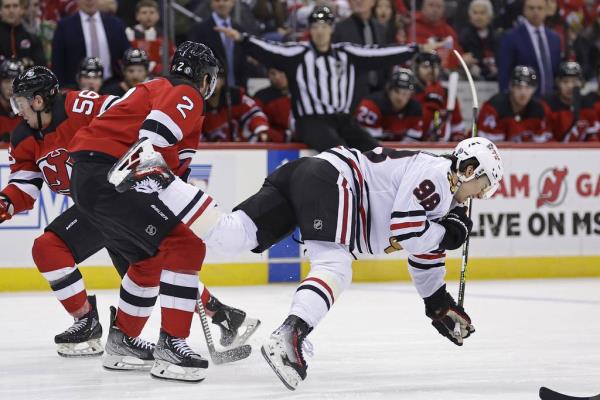 Blackhawks center Co<em></em>nnor Bedard falls to the ice after being checked by Devils defenseman Brendan Smith during the first period Friday in Newark, N.J. Bedard suffered a fractured jaw on the play and will be out indefinitely. The Devils won 4-2.