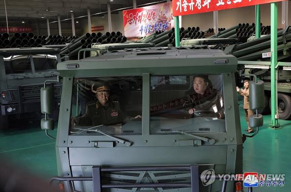North Korean leader Kim Jong-un (R) drives a vehicle designed to carry a 240mm multiple rocket launcher system during his visit to arms factories on May 11-12, 2024, in this photo carried by the Korean Central News Agency on May 13. (For Use o<em></em>nly in the Republic of Korea. No Redistribution) (Yonhap)