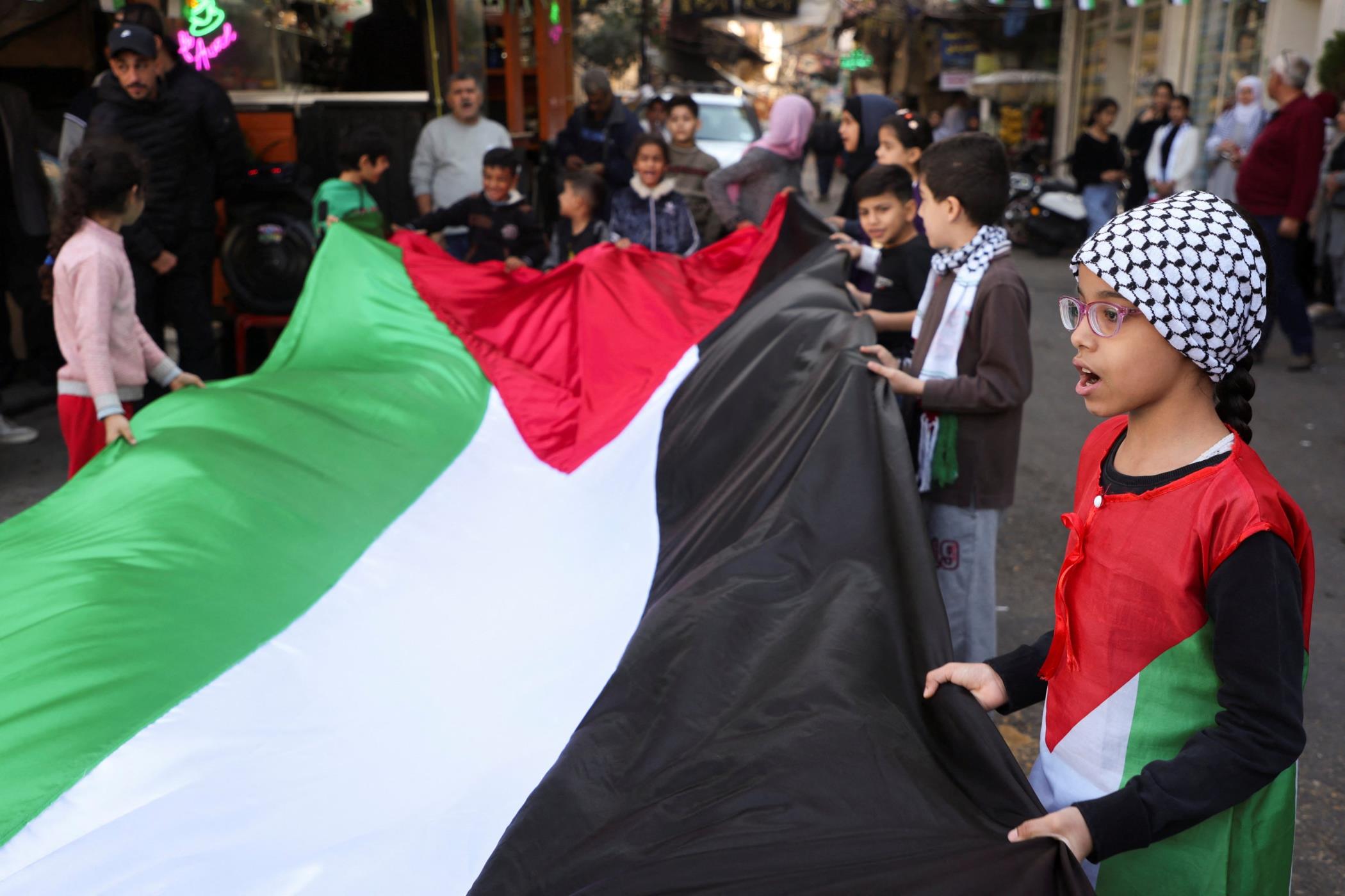 Children hold a Palestinian flag during a sit-in, in respo<em></em>nse to the global call for a strike in solidarity with Gaza, Burj al-Barajneh refugee camp, Beirut, Lebanon, Dec. 11, 2023. (Reuters Photo)